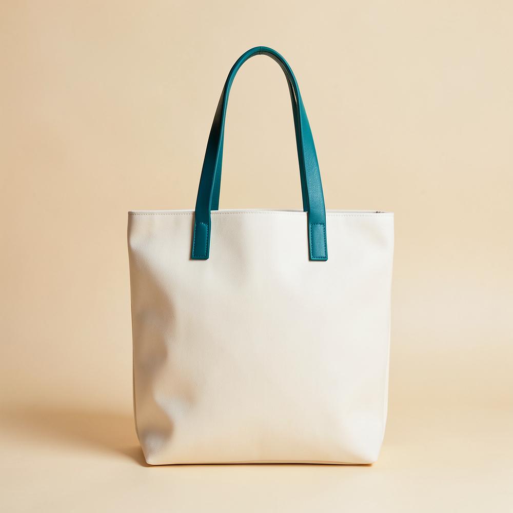 Ivory canvas tote bag with teal leather handles on a warm background